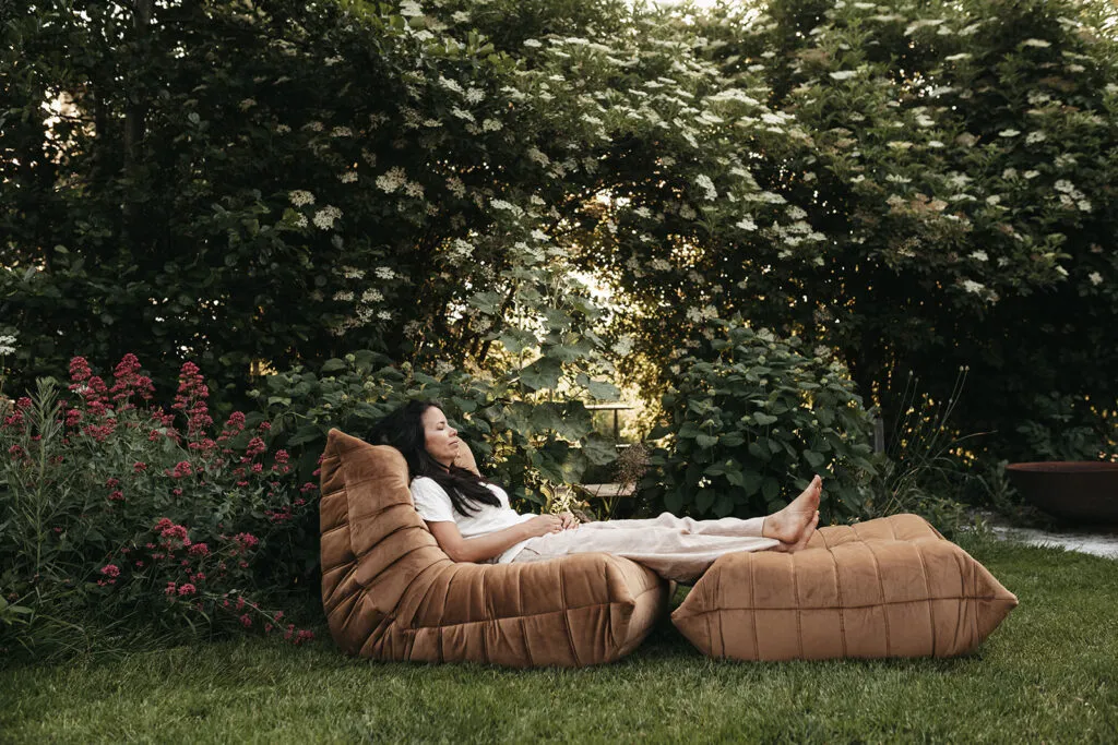 marika sitting on a couch on the grass under a tree